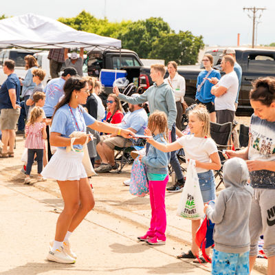 Young woman handing out items to children at a parade